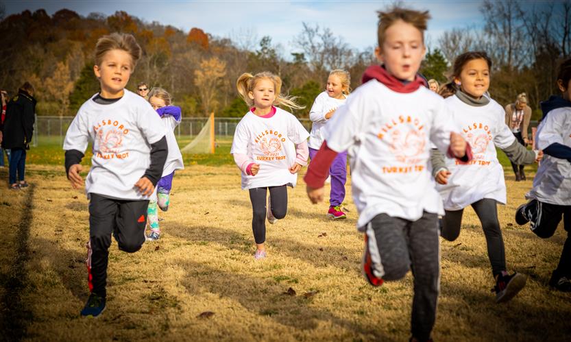 Students run down the side of a football field